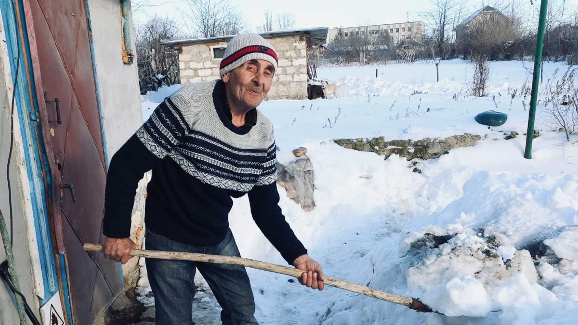 Elderly man shoveling winter snow