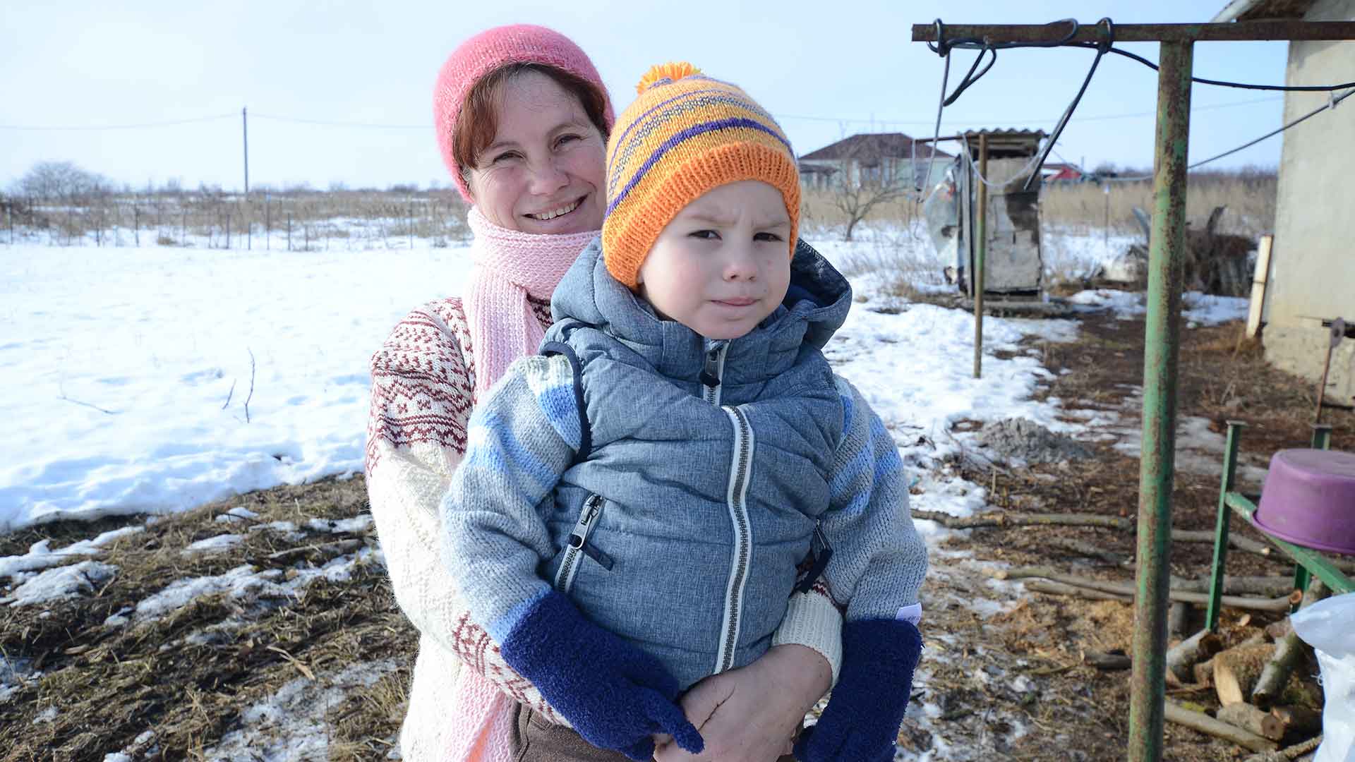 A woman and child stand in the snow.