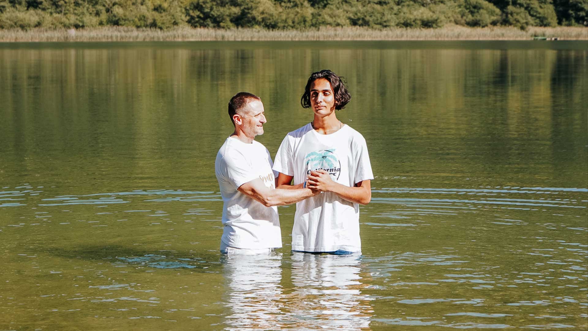 Two people stood in a lake for a baptism